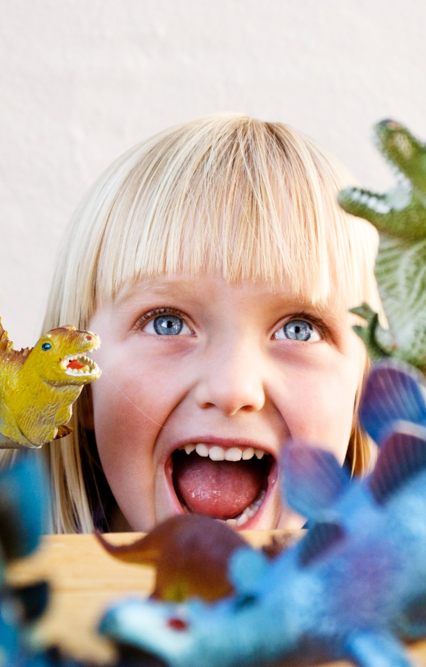 cute blonde toddler roars at her ferocious toy dinosaurs picture id154925745